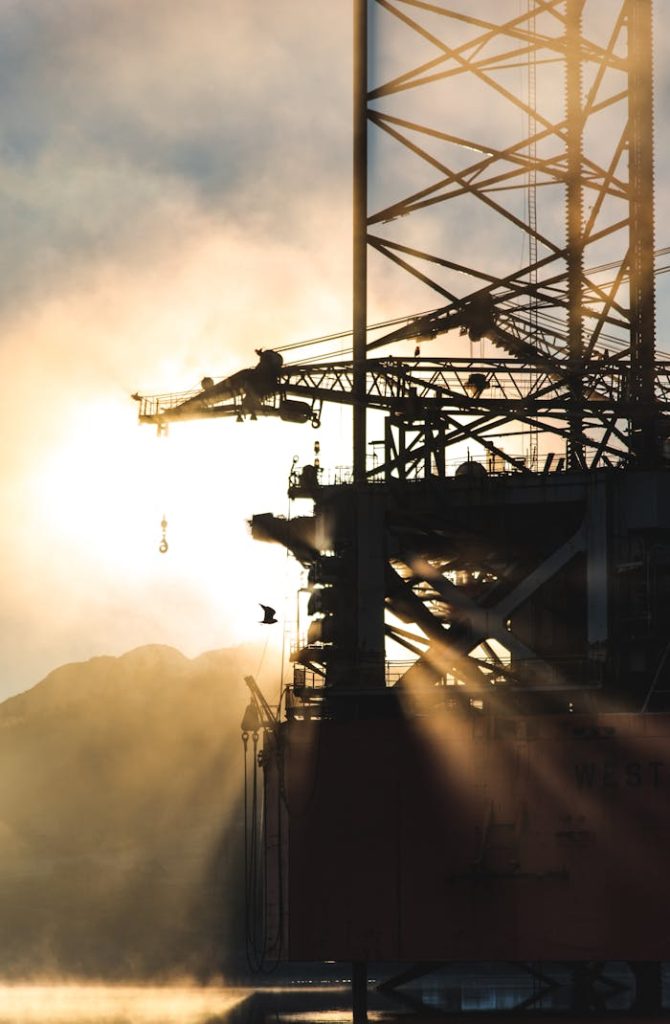 photo-of-oil-rig-platform-1716008 Dramatic silhouette of industrial machinery against a foggy morning sunrise, capturing the essence of heavy industry.
